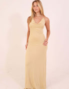 Mulher vestindo Vesstido Longo Malha Iris - Areia com decote cascateado e design elegante.