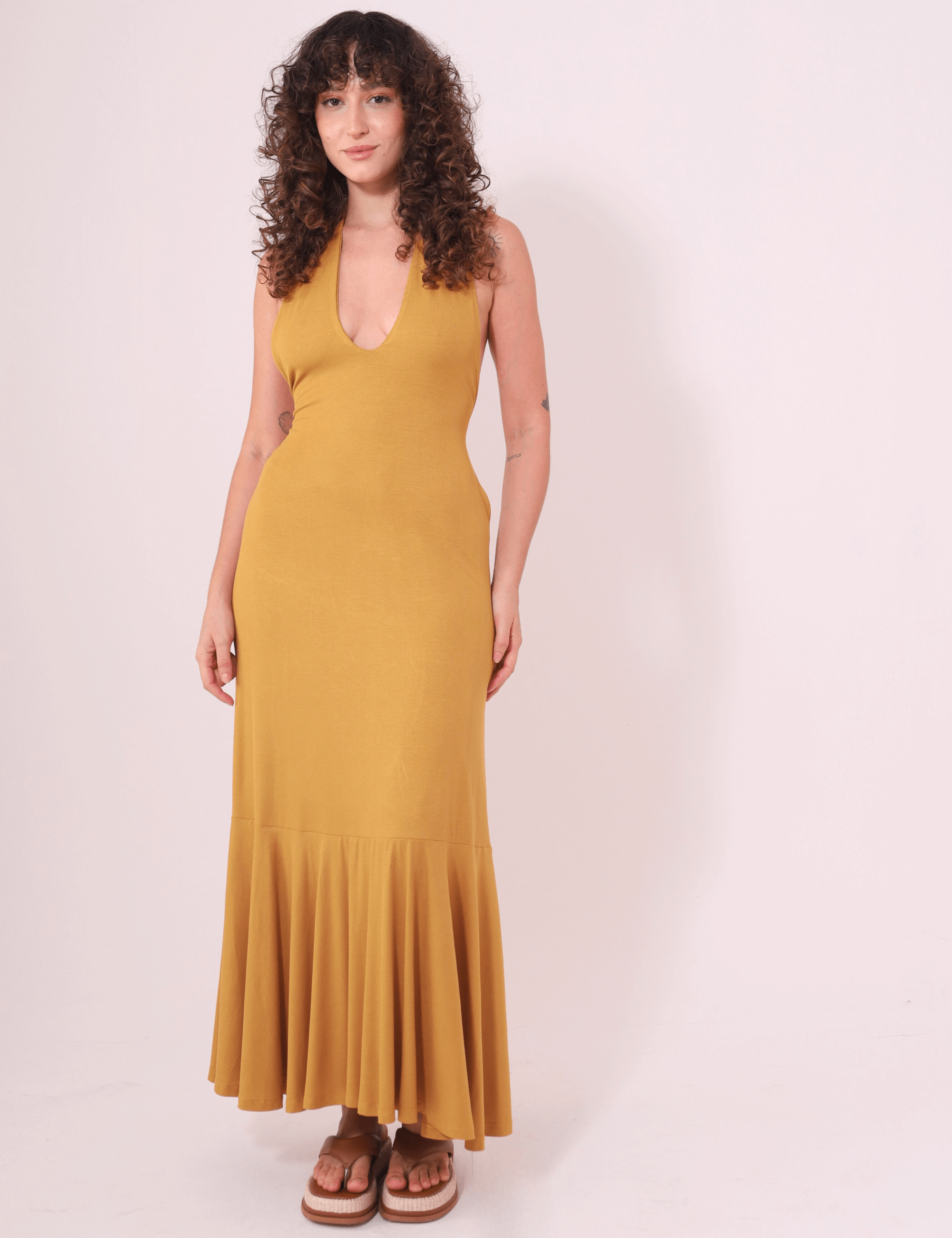 Vestido Longo Serena - Caqui da Greenish com decote profundo e jabô, mulher usando vestido fluido e confortável em fundo claro.