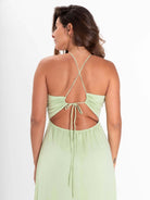 Modelo usando o vestido midi Alex verde claro da Greenish, com detalhes de amarração nas costas.