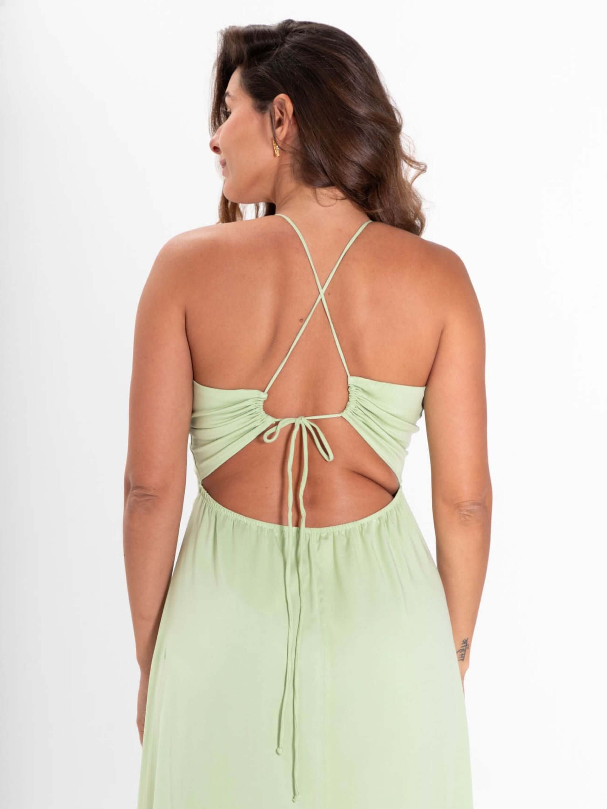 Modelo usando o vestido midi Alex verde claro da Greenish, com detalhes de amarração nas costas.