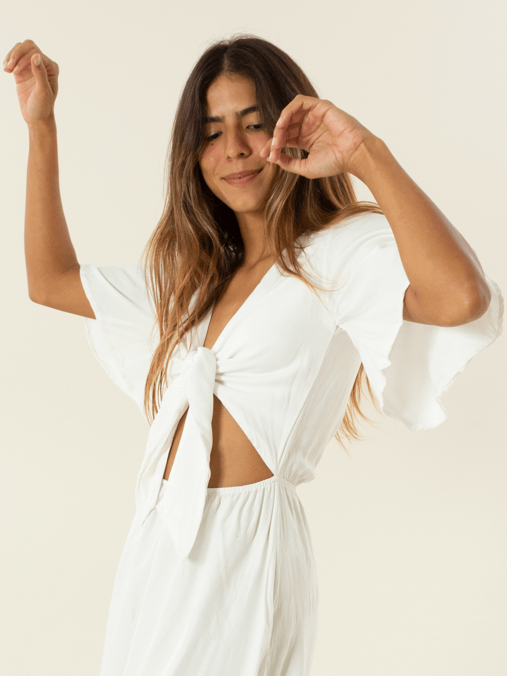 Modelo usando vestido midi Capri off white da marca Greenish, com mangas largas e detalhes elegantes.