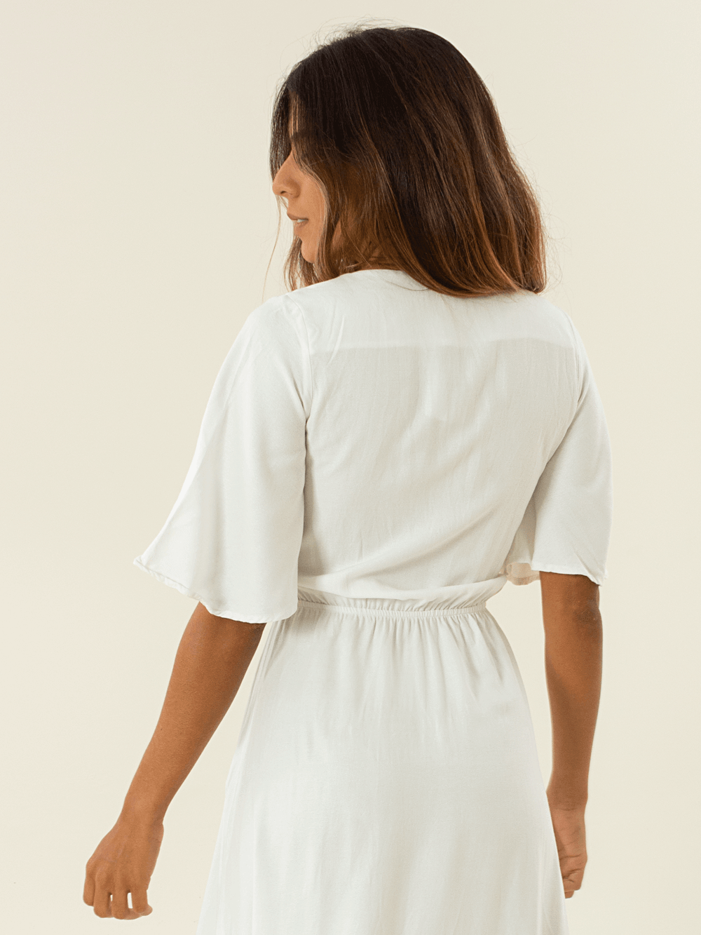 Modelo usando vestido midi Capri off white da marca Greenish, vista traseira, elegância e conforto.