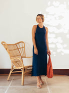 Modelo usando vestido midi Frankie azul marinho da Greenish, estilo sofisticado e moderno, com bolsa vermelha.