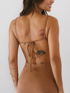 Modelo usando vestido midi Marley da Greenish, mostrando detalhes das alças ajustáveis e design elegante em marrom.