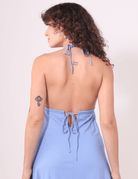 Mulher de costas vestindo Vestido Midi Tarsila Azul Claro da Greenish com alças finas amarradas, destacando elegância e conforto.