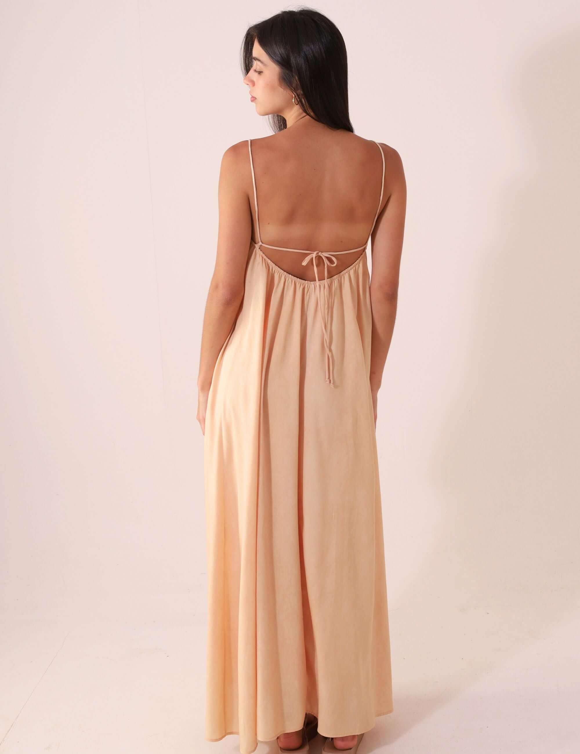 Mulher vestindo VESTIDO MIDI THÁ - BEGE da Greenish, destacando caimento suave e alças ajustáveis em cenário minimalista.