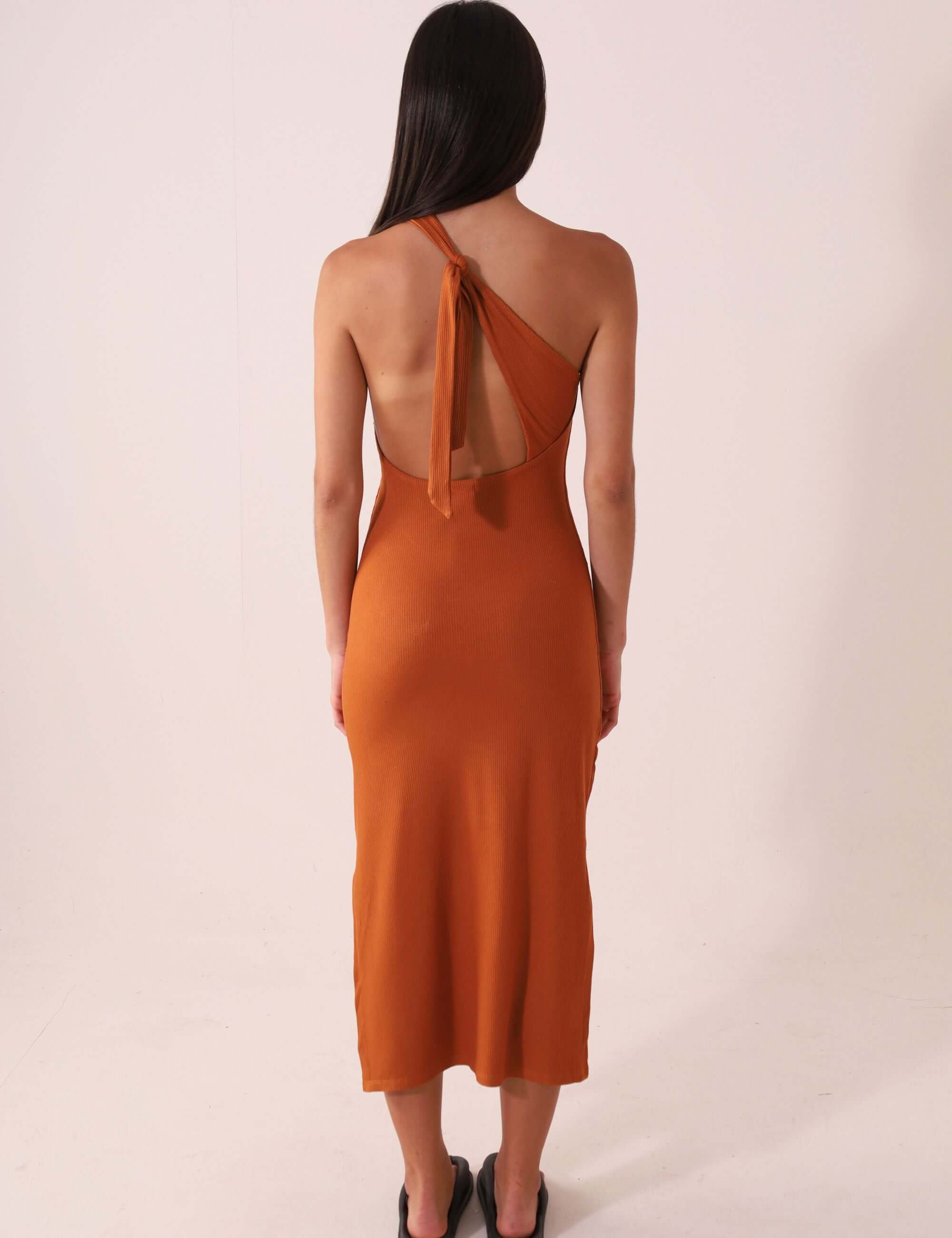 Vestido Monique – Cacau em design midi com um ombro só, destacando a silhueta e fluidez com amarração charmosa e fendas laterais.